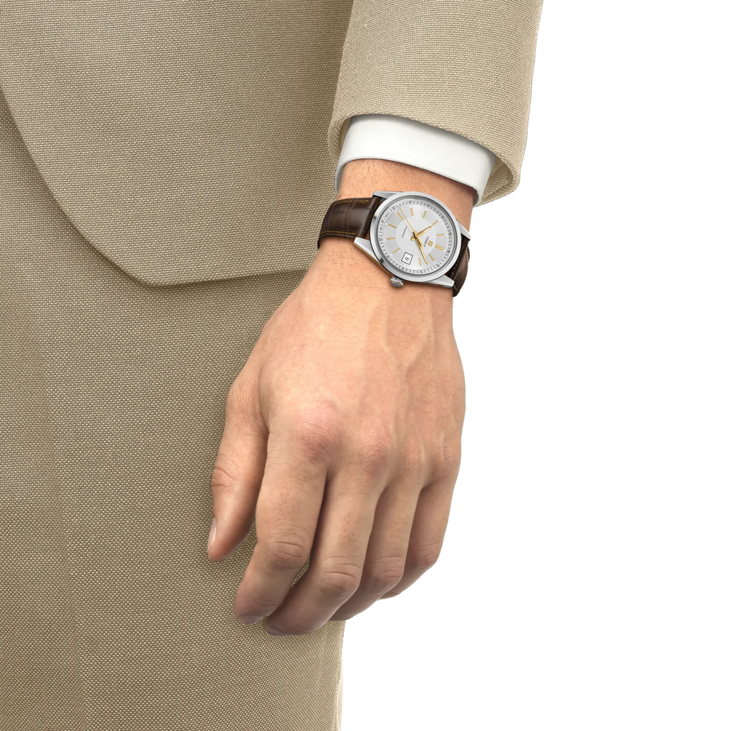 Lifestyle-Aufnahme einer Tissot Heritage Visodate Herrenuhr mit silbernem Zifferblatt und braunem Lederarmband am Handgelenk